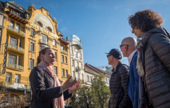 tour guide talking to group about large yellow building in background