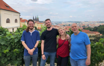 group of people smiling before skyline of prague city