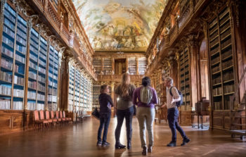 group of people in old library looking up at painted ceiling