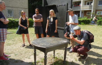 The group surround a table in an outside gallery.