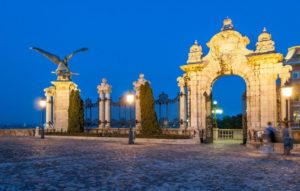 ornate gate with statues litup at night