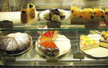 A glass cabinet filled with different cakes.