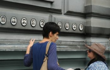 Small photographic portraits of people on the outside of a building.