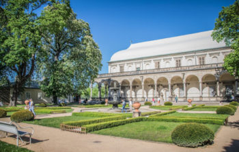 large white house with white eaves and fountain amongst garden