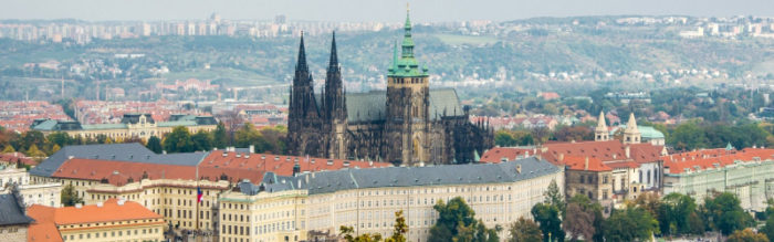 distant view of dark brick church with green roof steeple and castle complex surrounds