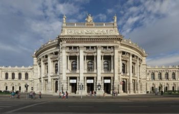 Front of a grand, pillared building, golden details.