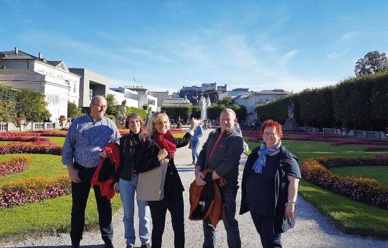 a group of tourists with a guide smiling in the Mirabell Gardens