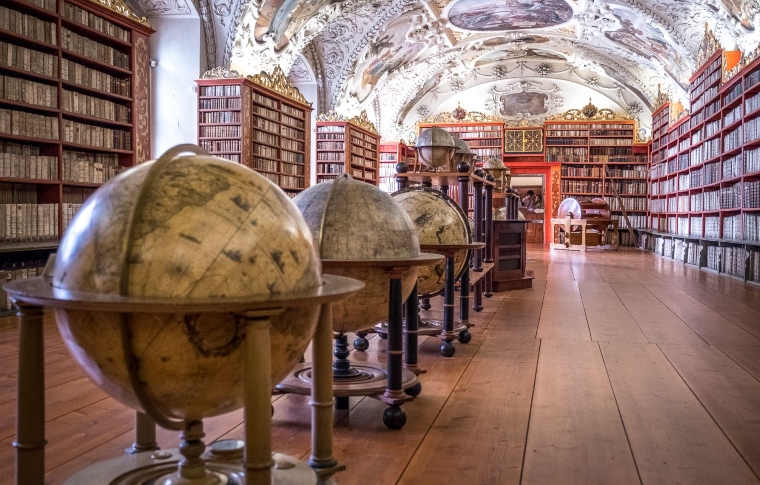 a row of globes between the bookcases in a Baroque library hall