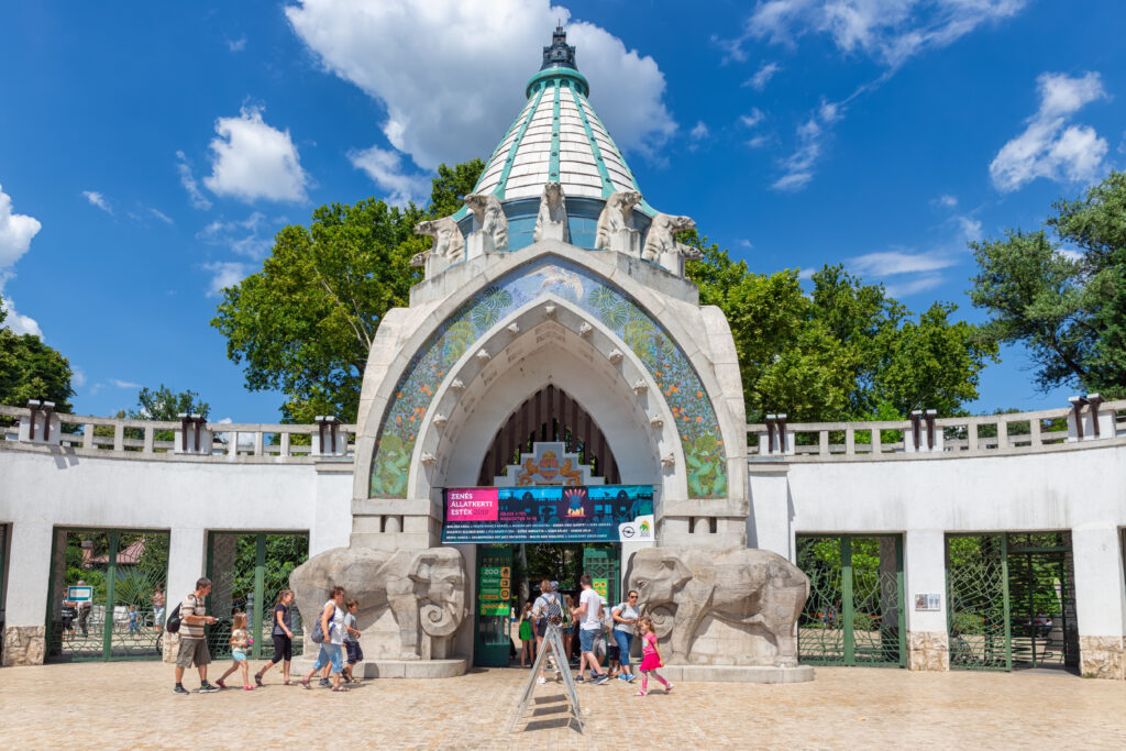 The entrance of Budapest zoo on a sunny summer day, with people entering through the doors