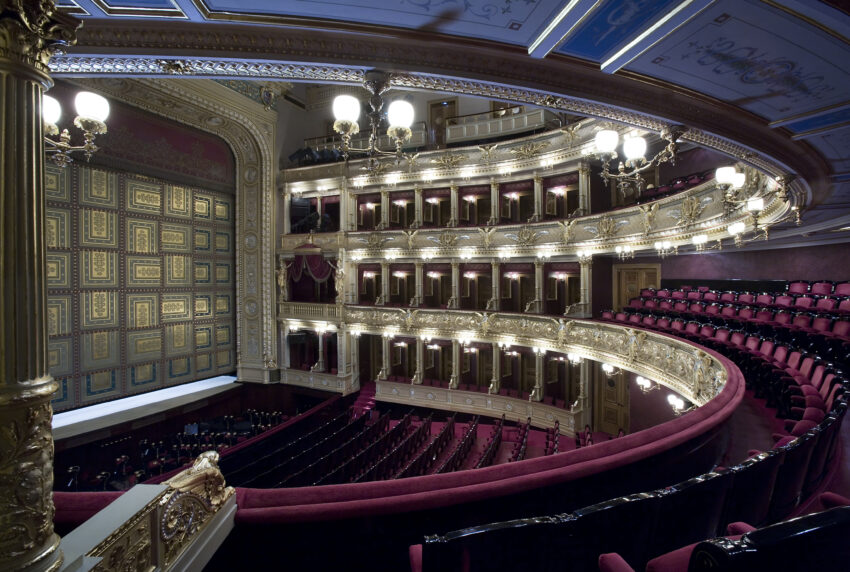 The interior of the National Theatre in Prague, Czech Republic, with rows of seats curving around the stage